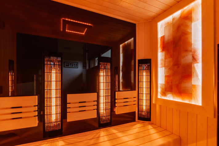 Infrasauna s himalájskou solí Pohled do interiéru moderní infrasauny, která intenzivně září hřejivým oranžovo-červeným světlem.