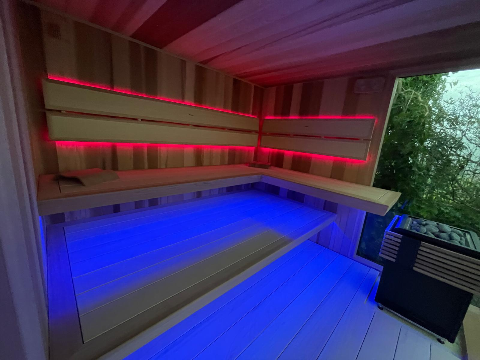 Venkovní sauna s odpočívárnou Prémiový interiér Diamond – zážitek pro tělo i smysly Srdcem celé sauny je interiér v prémiové řadě Diamond, určený pro ty, kdo nechtějí dělat kompromisy. Lavice s masivními hrany z cenného červeného cedru jsou ergonomicky tvarované, čímž zajišťují maximální komfort při sezení i ležení. Vnitřní výstelka je tvořena širokými lamelami z africké vrby abachi – dřeva známého svou mimořádnou jemností na dotek, nízkou tepelnou vodivostí a vizuální čistotou. Levitující lavice bez viditelných podpěr navozují pocit vzdušnosti a lehkosti, zatímco decentní LED podsvícení opěrek zad ve dvou liniích a podsvícení pod lavicemi vytváří příjemnou atmosféru a zvýrazňuje kontury celého prostoru.